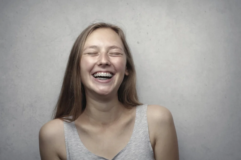 Young woman laughing with her eyes closed against a grey background