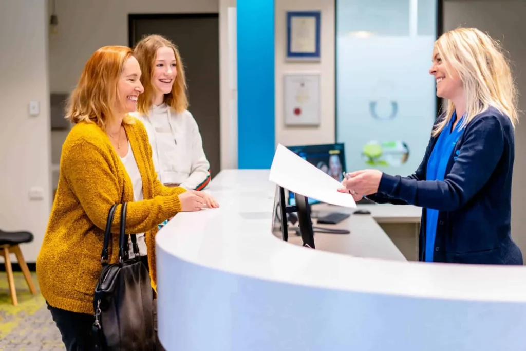 Two patients being served at the Central Coast Orthodontics reception desk